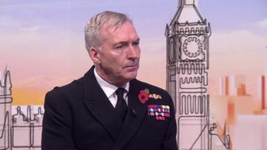 Admiral Sir Tony Radakin wearing a black jacket and black tie, a poppy and his military emblems