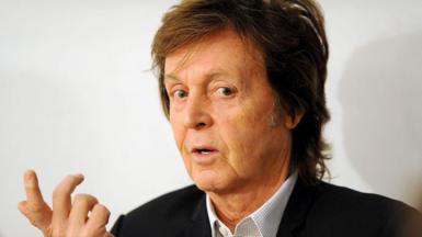 Headshot of musician Paul McCartney, wearing black blazer and open-necked shirt, taken in 2014 