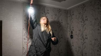 Yulia hangs a light in her home