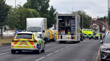 A number of police vehicles close off  dual carriageway in Merseyside. The road has trees lined down the middle