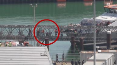 A group of migrants walking over a bridge from a Border Force boat