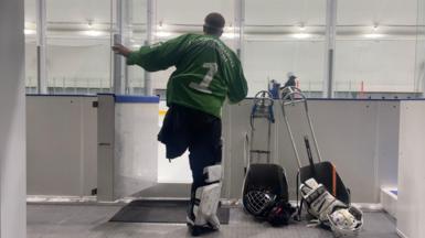 A Russian ice hockey player with one leg enters the ice rink, wearing pads and a green jersey 