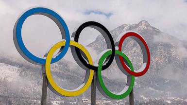 The Olympic rings with a snowy mountain in the background
