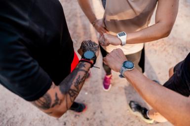 Three people wearing smart watches and looking down at them