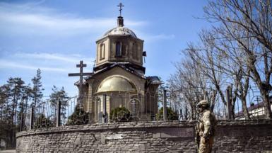 Russian soldier walks past a church in Volnovakha during his patrol