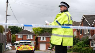 Police officer stands in front of a police cordon on Ashlyn Close
