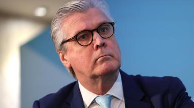 Malcolm Offord, who has grey hair brushed back, in a close-up shot in front of a pale blue background.