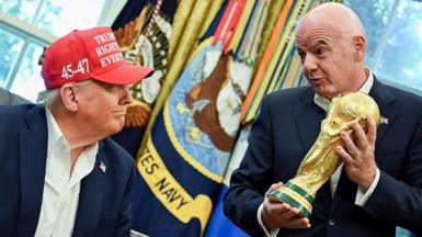 Donald Trump looking at Gianni Infantino holding the World Cup