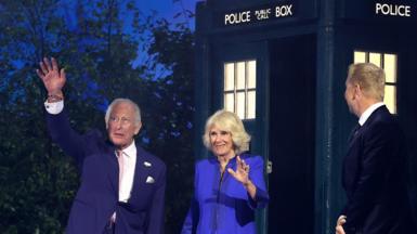 King Charles III and Queen Camilla emerge from a Tardis at the Commonwealth Games opening ceremony and wave, as a kilted Sir Chris Hoy greets them