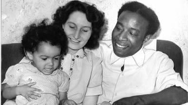 A black and white photograph shows a man, Rupert Allen, sat next to his wife, Marguerite and their daughter Pearl, in September 1955. Rupert was one of the first arrivals in Wolverhampton on the Empire Windrush.