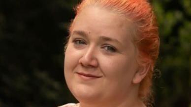 A close up photo of Rhiannon Whyte, showing her with orange-dyed hair and a multi-coloured vest-type top.