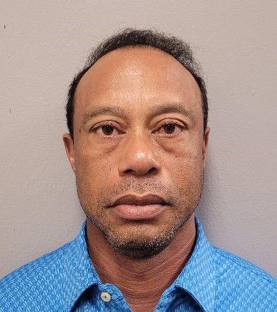 Tiger Woods looks into the camera as he wears a blue top and poses for a mugshot.