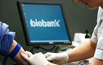 Nurse taking blood from person as biobank logo appears on screen in background.