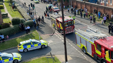 A view from the window of a building where the fire took place shows fire engines and police cars on the ground, with a large crowd lined up along the opposite road.