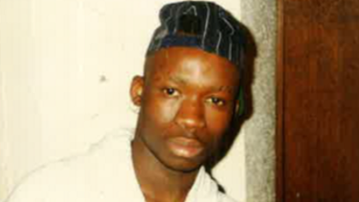 A close up photo of James, who is looking into the camera and wearing a cap.