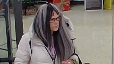 Rachael Cole wearing a white and black wig and glasses as she walks around a supermarket.