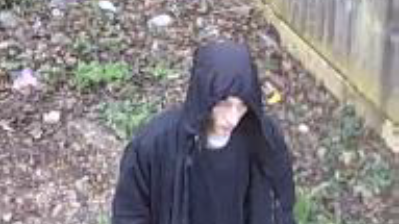 CCTV footage of a man wearing a black hooded jacket walking 