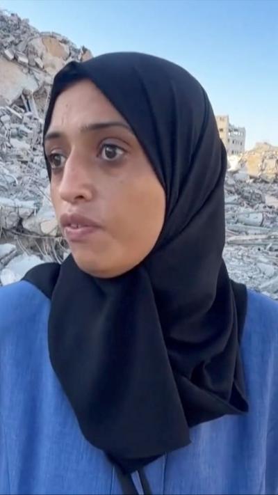 Gazan woman standing in front of rubble