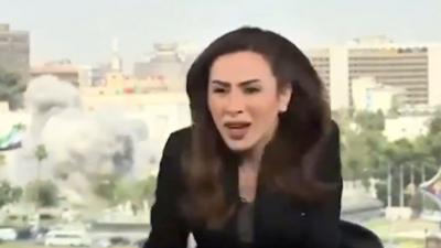 Female news presenter looks shocked as en explosion occurs behind her