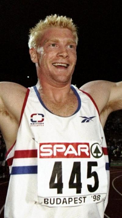 Young Iwan Thomas wears Team GB vest and is grinning as he crosses the finish line after a race