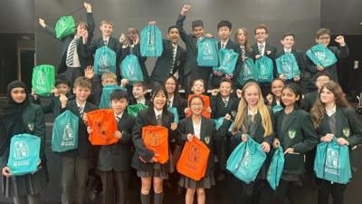 School children holding rucksacks. 