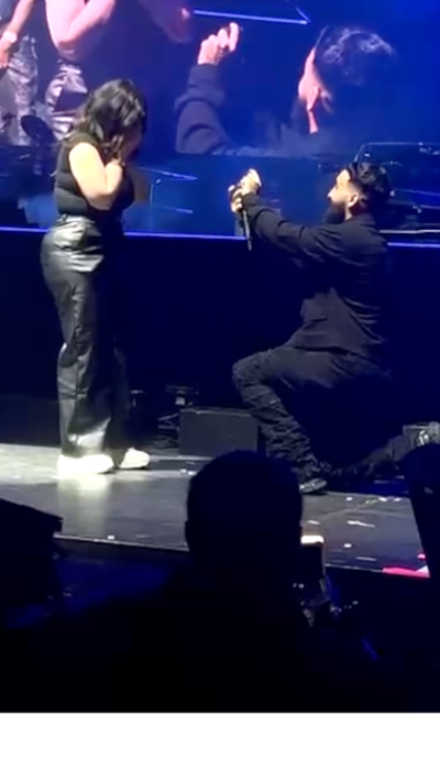 A man proposes to a woman on a stage in the O2 arena.