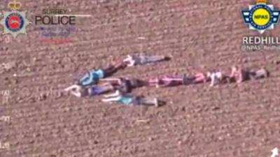 Children lying down in field, forming an arrow shape