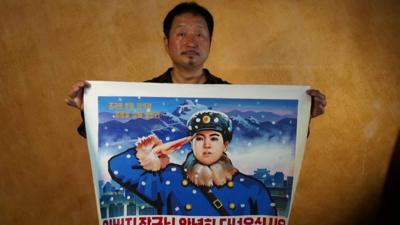 Choi Sangkyun holding North Korean propoganda art