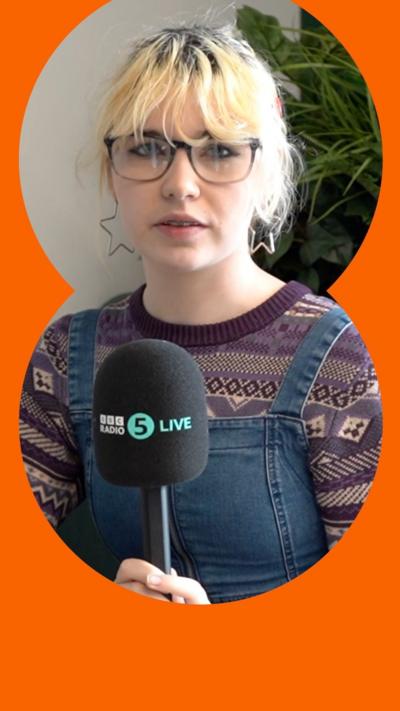 A teenage girl holds a 5 Live mic. She has short blonde hair and wears a purple patterned jumper and denim dungarees