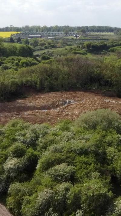 A drone image showing a large waste dump. It is surrounded by woodland.