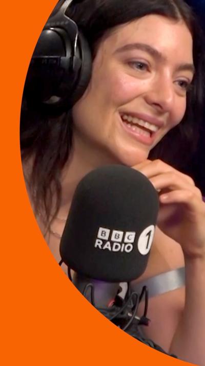 Lorde wearing headphones and sitting in front of a Radio 1 mic
