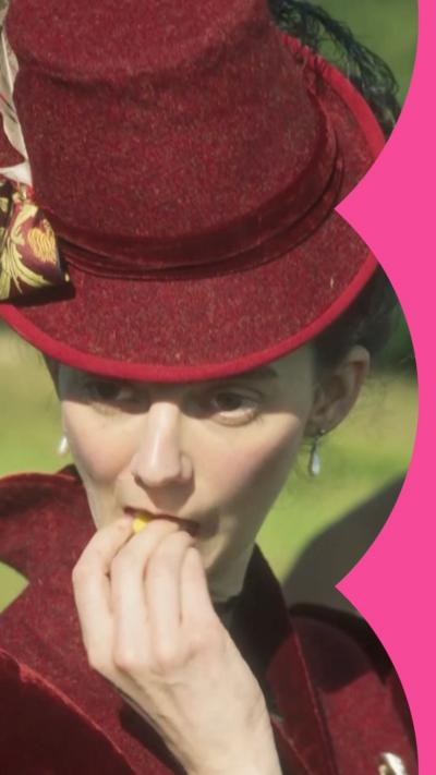 A woman in a red had eats a flower