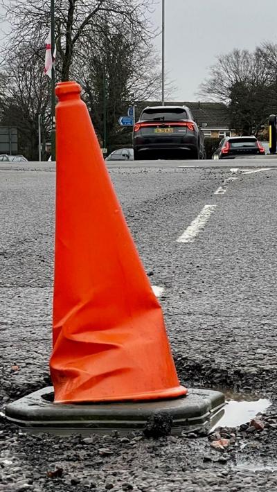 Orange traffic cone in a pothole to warn drivers
