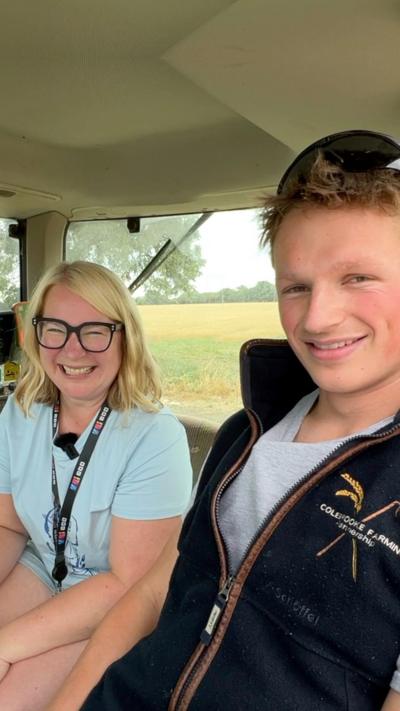 A woman and a man smiling while sitting in a tractor cab.