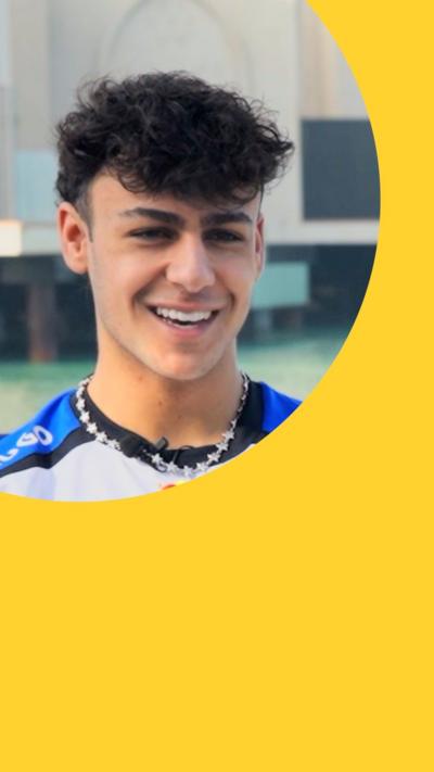 Arvid Lindblad smiles. He has curly black hair and wears a blue and white T-shirt with a silver necklace