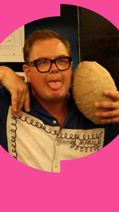 Alan Carr making a face holding a model dinosaur egg