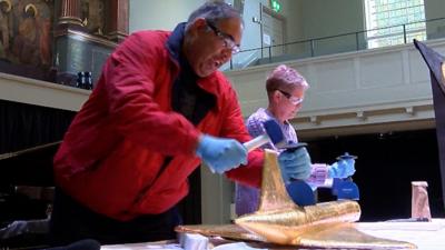 People smashing up chocolate sculptures with a hammer