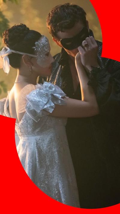 Benedict Bridgerton in black clothes, kissing the hand of Sophie Baek, in a white dress. Both are masked.