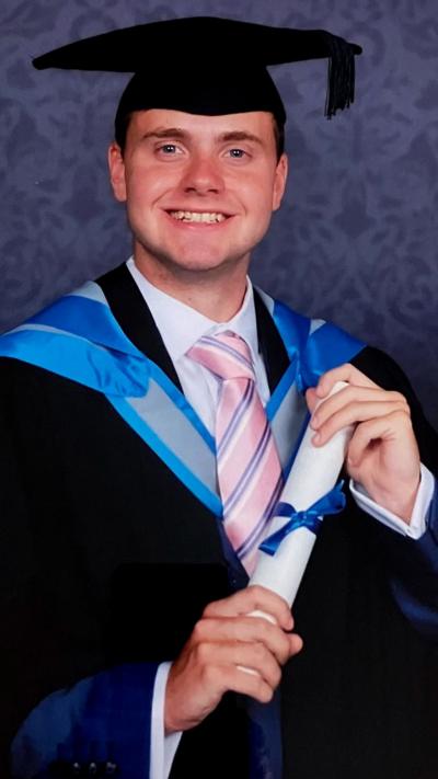 Missing student Jack O'Sullivan's graduation photo - wearing a mortar board and gown with a degree rolled up in his hands