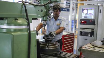 An employee operates a metal lathe at a factory in Chennai, India