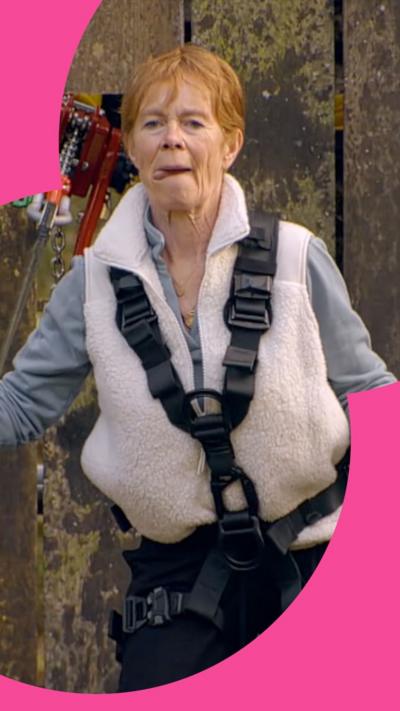 Celia Imrie's tongue sticks out as she wears a harness while on a bridge during a challenge