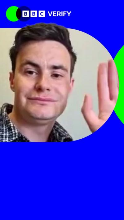 Reform Councillor George Boyd waves to the camera. He is wearing a collared shirt. He is imposed over the BBC Verify colours and branding. 