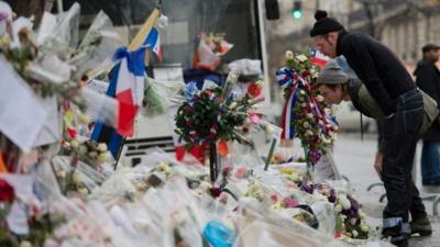 Members of Eagles of Death Metal look at floral tributes