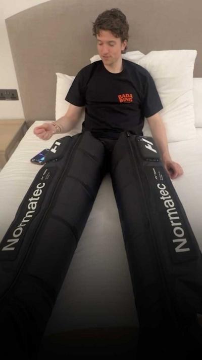 Greg James lies on a bed with leg compression boots on.