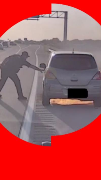 Police officer with his hand on the left door handle of a car with flames underneath.