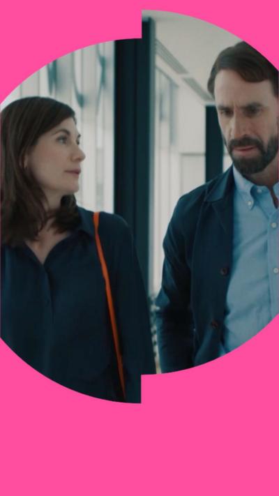 Jodie Whittaker has shoulder length, dark hair and is wearing a dark blue v-necked top. Joseph Fiennes has short brown hair, a beard and a moustache. He is wearing a light blue shirt with a dark blue jacket over it.