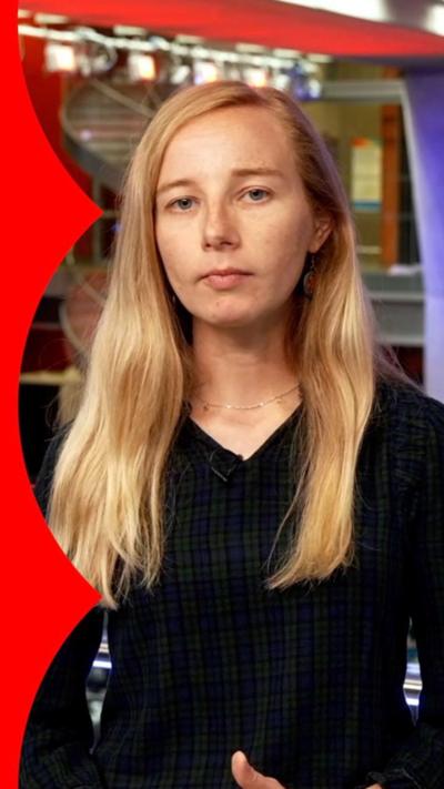 A woman, Verify presenter, with long blonde hair, in the BBC newsroom.