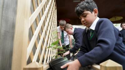 Children planting by a wooden trellis