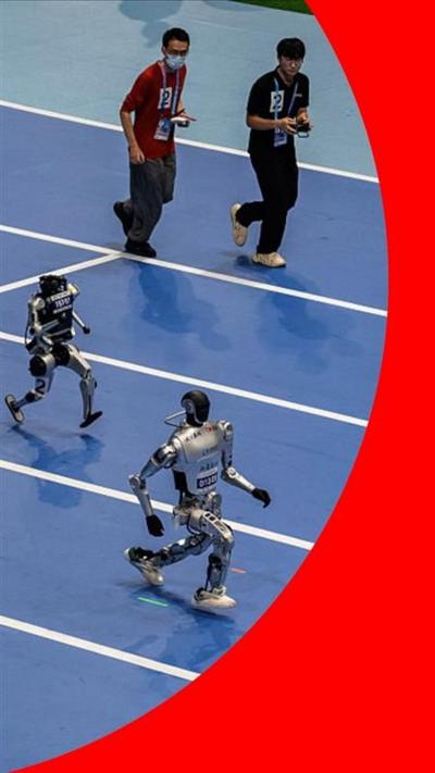 Two humanoid robots on a blue race track. Two men look on behind them