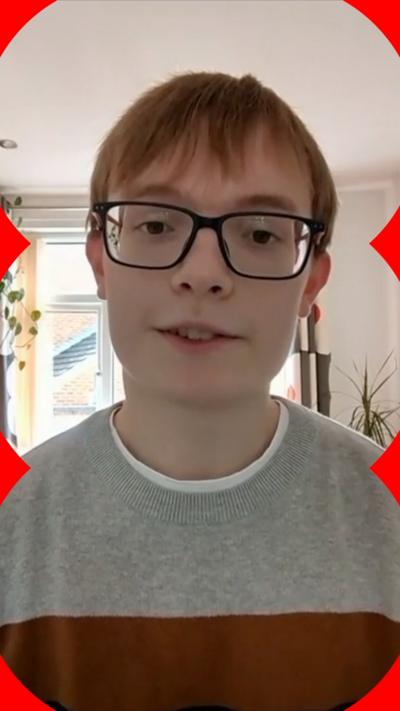 Boy with ginger hair and glasses looks at camera